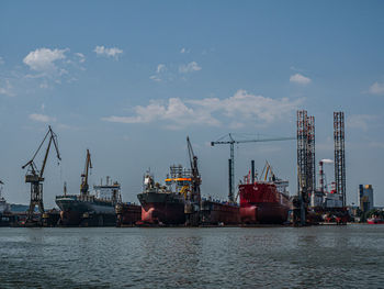 Cranes at commercial dock against sky