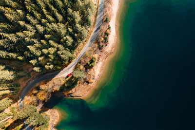 Aerial view of car on road by forest and lake in autumn