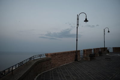 Street light by sea against sky