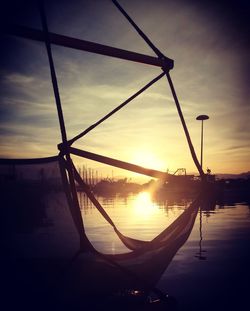 Silhouette boat in lake against sky during sunset