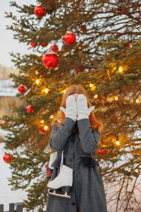 Rear view of woman standing by christmas tree