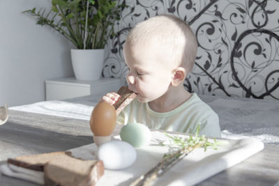 A child, a little boy bites one piece of bread with his eyes closed for easter.