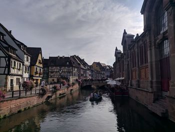 Canal amidst buildings in city against colmar france