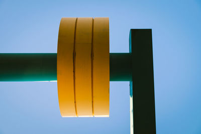 Low angle view of yellow metal against clear blue sky