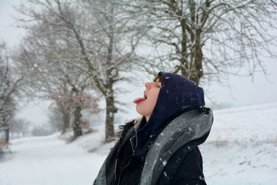 A girl in nature, catches snowflakes with her tongue