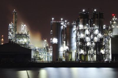 Illuminated factory against sky at night