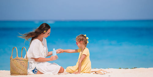 People sitting on beach by sea against sky