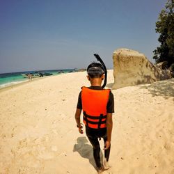 Rear view of boy on beach against sky