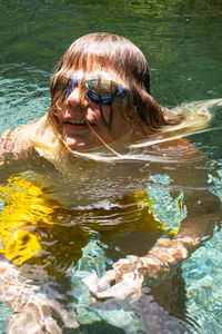 Portrait of funny teenage with hair across face in swimming pool.