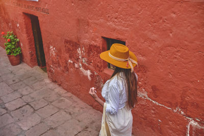 Rear view of woman standing against wall