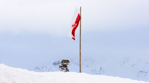 Red flag on snow against sky