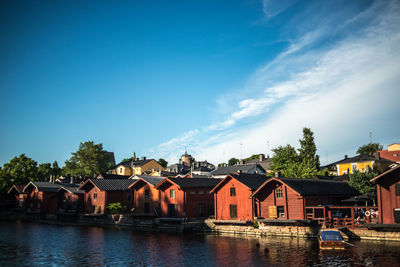 Houses by trees against blue sky