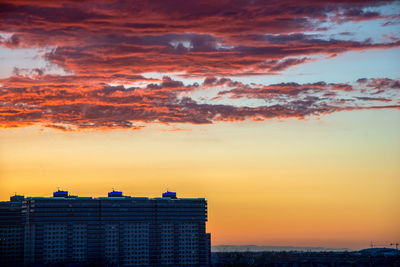 Buildings against dramatic sky during sunset