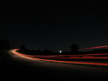 Light trails on road against sky at night