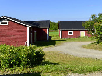 House and trees on field against clear sky