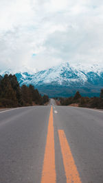 Surface level of road by snowcapped mountains against sky