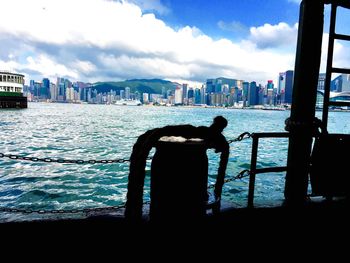 Silhouette man by sea against sky in city