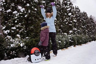 Happy family, mother, son and cat in backpack walking on the snowy alley in winter snowy nature