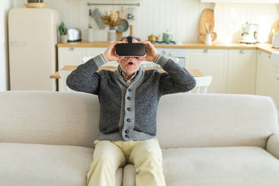 Young woman using phone while sitting on sofa at home