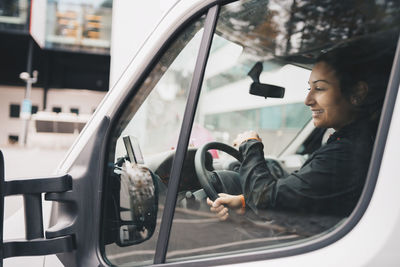 Reflection of man sitting in side-view mirror