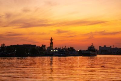 Buildings at waterfront during sunset