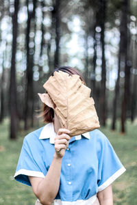 Midsection of woman standing by tree trunk in forest