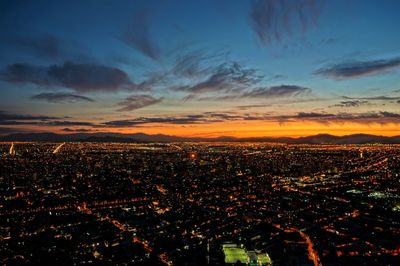 Aerial view of illuminated cityscape against sky at sunset