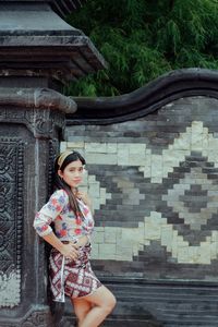 Portrait of young woman standing against trees