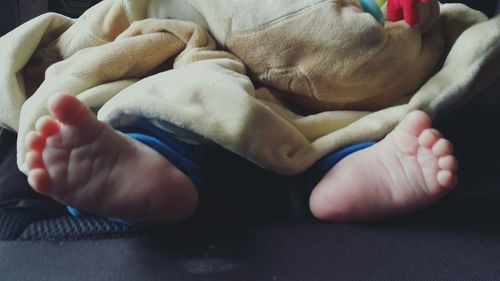 Low section of baby boy relaxing on bed