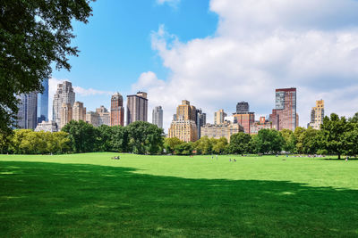 Golf course against buildings and sky in city