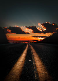 Surface level of road against sky during sunset