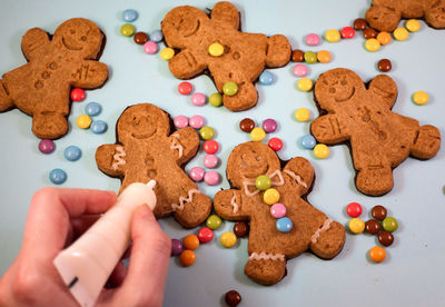 High angle view of gingerbread cookies on table being decorated with icing and smarties