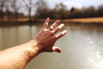 Close-up of hand against lake