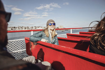 A young woman wearing glasses smiles while riding a ferry in maine.