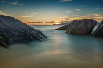 Scenic view of rocks in sea against sky during sunset