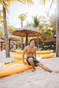 Portrait of shirtless man sitting in boat at beach