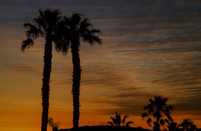 Silhouette palm trees against romantic sky at sunset