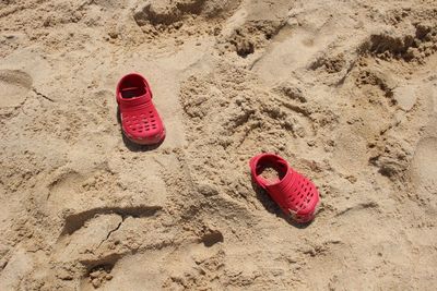 High angle view of child red shoes on sand