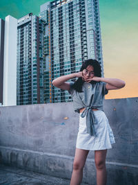 Full length of woman standing against modern building in city