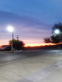 Cars on road against sky during sunset