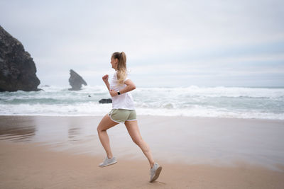 Side view of woman standing at beach against sky