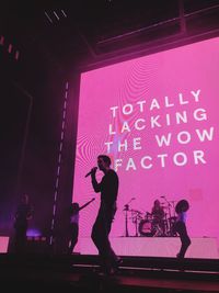 Silhouette man with arms raised standing on stage