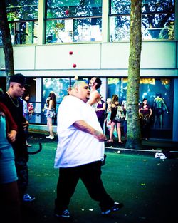 Rear view of girl holding people standing outdoors