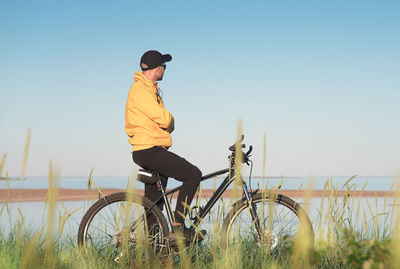 Side view of man riding bicycle against clear sky