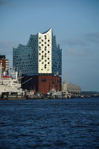 Sea by buildings against sky in city