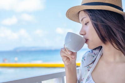 Young woman drinking coffee while sitting on the terrace of a cafe or restaurant in a hotel 
