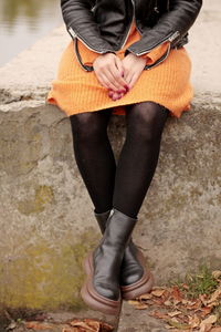 Woman sitting on the shore, female legs in a dress, female feet in boots