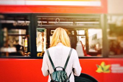 Rear view of woman sitting on railroad station