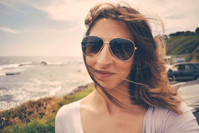 Portrait of woman wearing sunglasses against sea