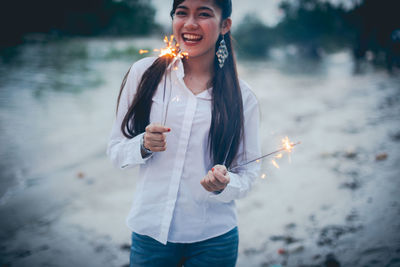 Young woman smiling while standing against black background